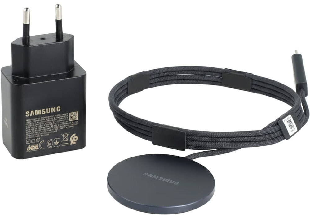 Na obrazie widoczna jest czarna ładowarka sieciowa z logo \'SAMSUNG\' oraz okrągła ładowarka indukcyjna z przewodem, również z logo \'SAMSUNG\'.