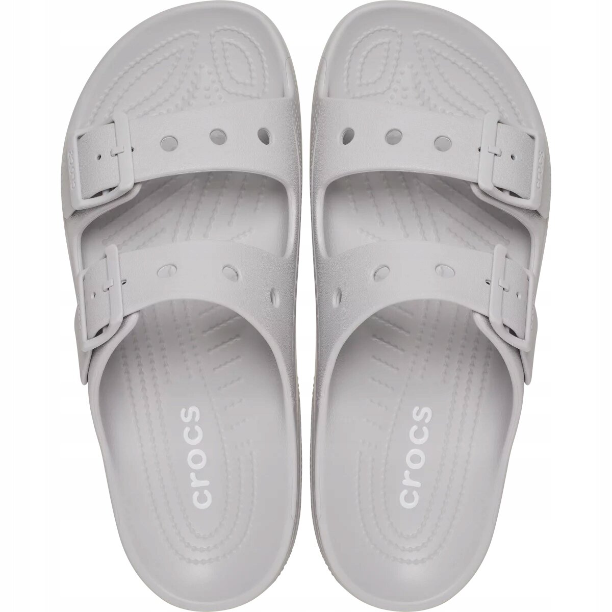 Para jasnoszarych klapek z dwoma regulowanymi paskami i widocznym logo \'Crocs\' na wkładce. Klapki mają perforacje na paskach i wzór na wkładce.