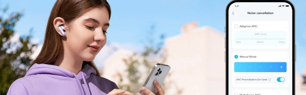 Osoba w fioletowej bluzie używa smartfona, mając w uszach białe słuchawki dokanałowe. Obok widoczny jest ekran telefonu z aplikacją do redukcji szumów, z opcjami \'Adaptive ANC\' i \'Manual Mode\'.