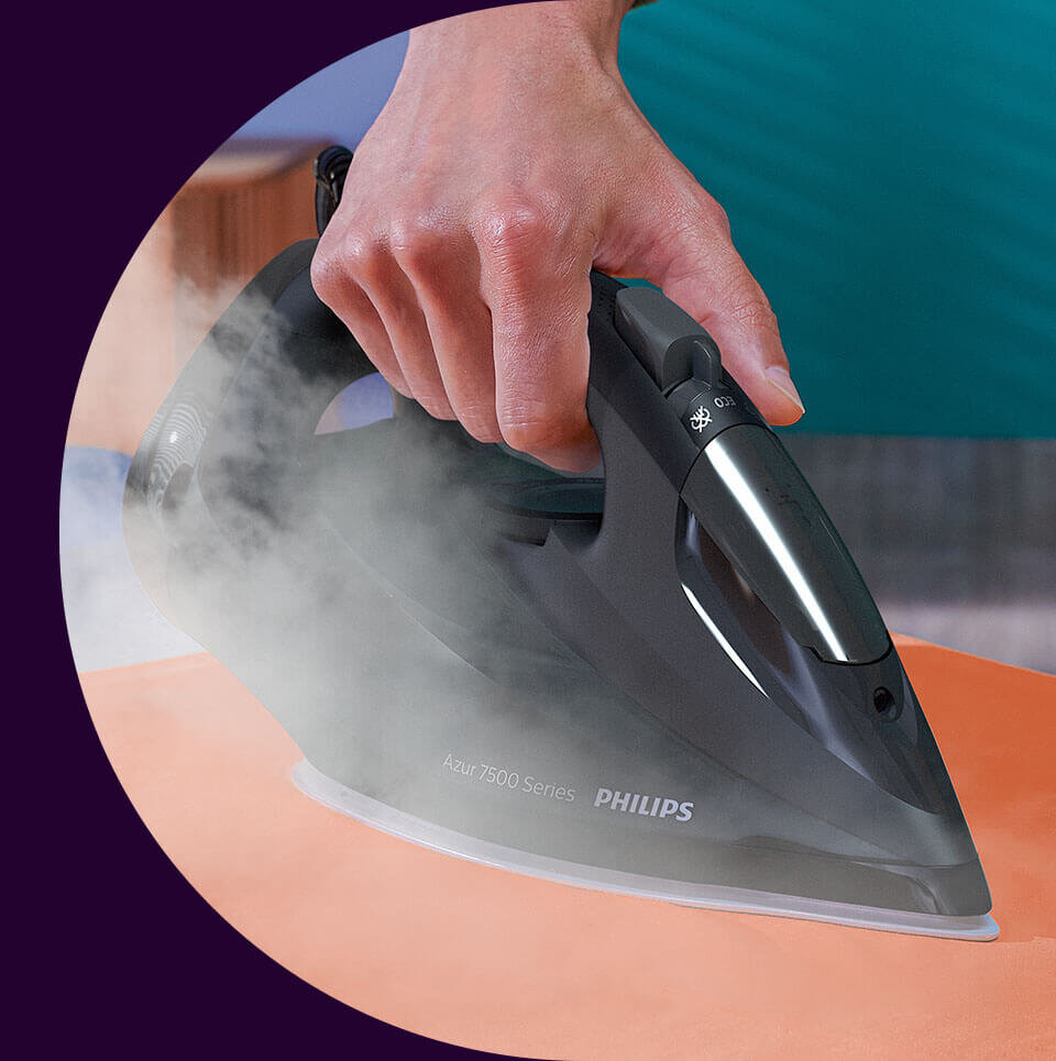 Osoba prasuje pomarańczowy materiał żelazkiem z napisem \'Azur 7500 Series PHILIPS\'. Z żelazka wydobywa się para.