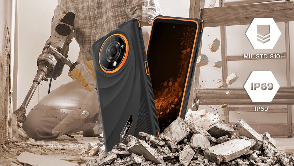 Smartfon z pomarańczowymi akcentami leży na gruzie, obok osoby używającej młota pneumatycznego. Na obrazie widoczne są oznaczenia MIL-STD-810H i IP69.