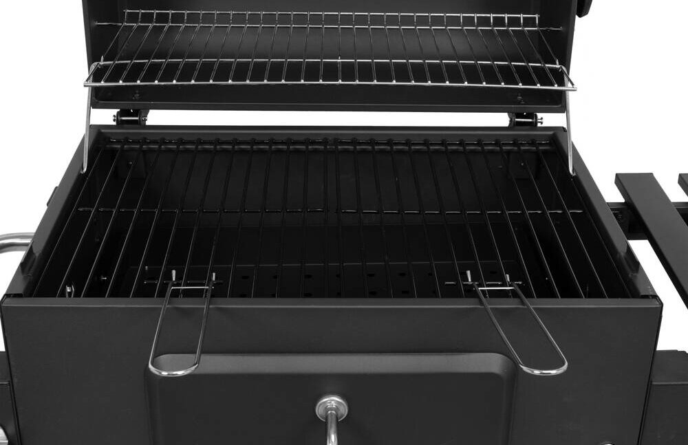Otwarty grill węglowy z dwoma poziomami rusztów, metalową pokrywą i uchwytami. Widoczne są również boczne półki i kółka ułatwiające transport.
