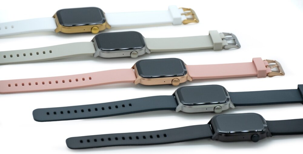 Na obrazie widoczne są pięć smartwatchy z prostokątnymi kopertami i różnokolorowymi paskami: biały, szary, różowy, granatowy i czarny. Każdy zegarek ma metalową kopertę i zapięcie na pasku.