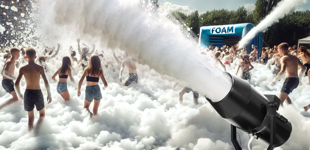 Na obrazie widać urządzenie generujące pianę, skierowane w stronę grupy ludzi bawiących się w pianie. W tle znajduje się niebieski namiot z napisem \'FOAM\'.