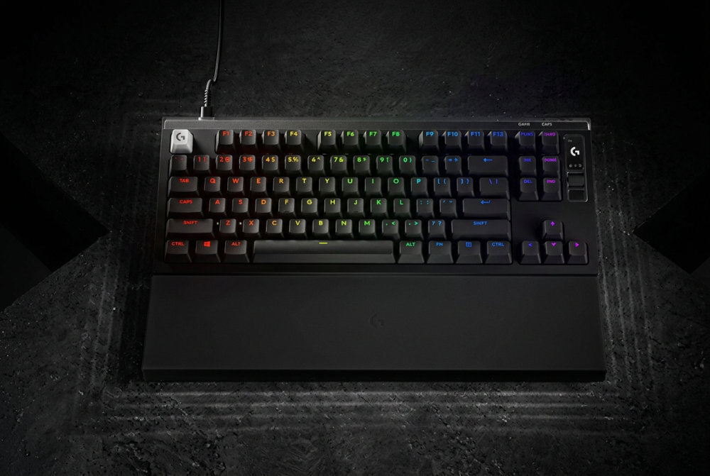 Klawiatura mechaniczna z podświetleniem RGB, z widocznym logo \'G\' w lewym górnym rogu. Klawisze mają różnokolorowe podświetlenie, a klawiatura jest podłączona kablem.
