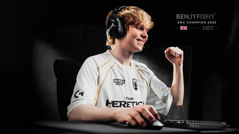 Osoba w białej koszulce z logo \'TEAM HERETICS\' siedzi przy biurku z klawiaturą i myszką, nosząc słuchawki. Obok widoczny jest tekst: \'BENJYFISHY EWC CHAMPION 2025\'.