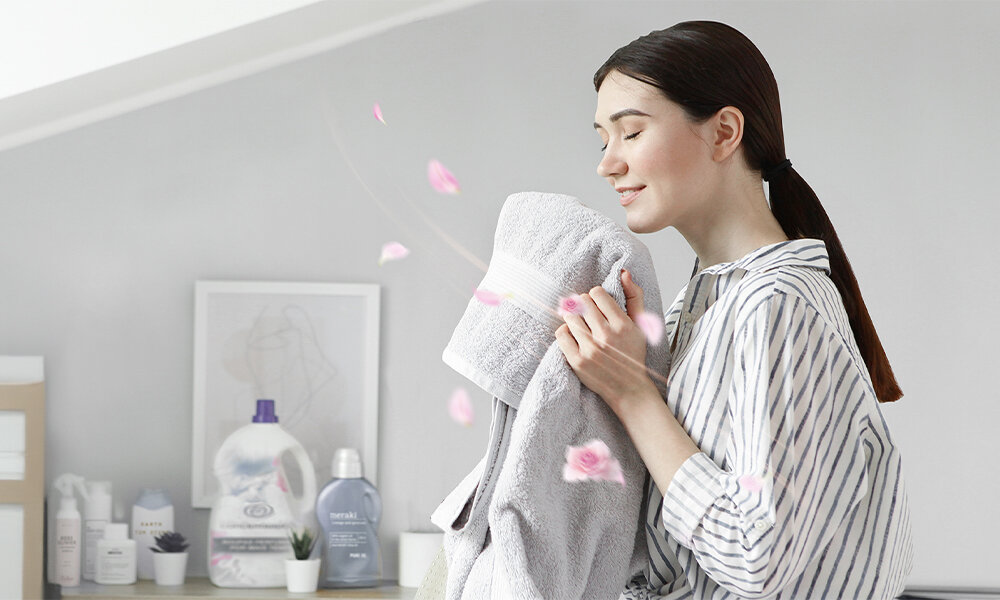 SUSZARKA MIDEA MD110H80D WW-PL Osoba trzyma świeżo wyprany ręcznik. Grafika nawiązuje do miękkości tkanin i przyjemnego zapachu po praniu suszarka 8 kg pompa ciepła klasa energetyczna A++ Health Guard Wool Refresh Air Fresh
