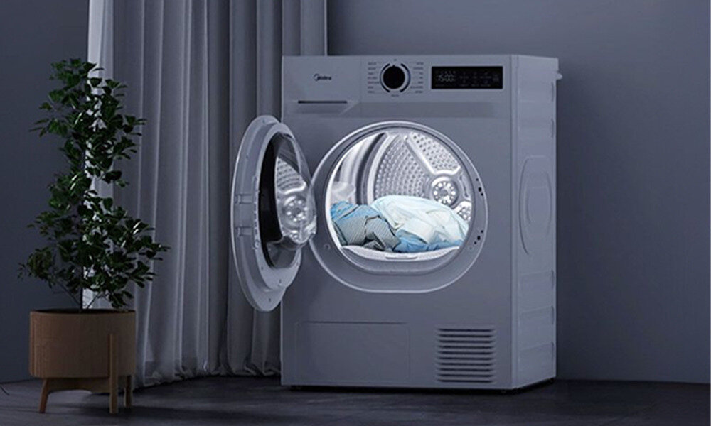 SUSZARKA MIDEA MD110H80D WW-PL Suszarka Midea z otwartymi drzwiami i oświetlonym bębnem. Grafika pokazuje wnętrze urządzenia oraz przygotowane do suszenia ubrania oświetlenie bębna wygodne wyjmowanie ubrań dobra widoczność komfort użytkowania
