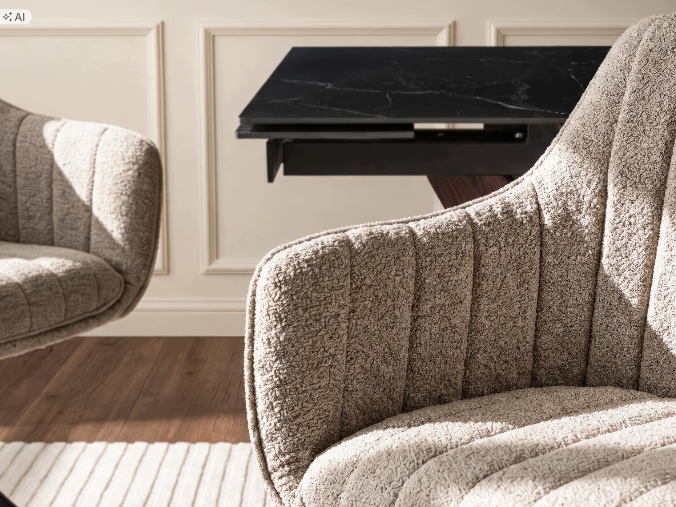 Na obrazie widoczne są dwa tapicerowane krzesła w kolorze brązowym z wyraźnym pikowaniem. W tle znajduje się stół z ciemnym, marmurowym blatem.