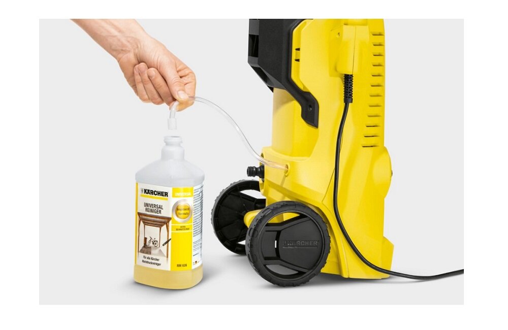 Osoba podłącza wężyk do butelki z płynem czyszczącym obok żółtej myjki ciśnieniowej. Na butelce widnieje logo \'KARCHER\' oraz napis \'UNIVERSAL REINIGER\'.
