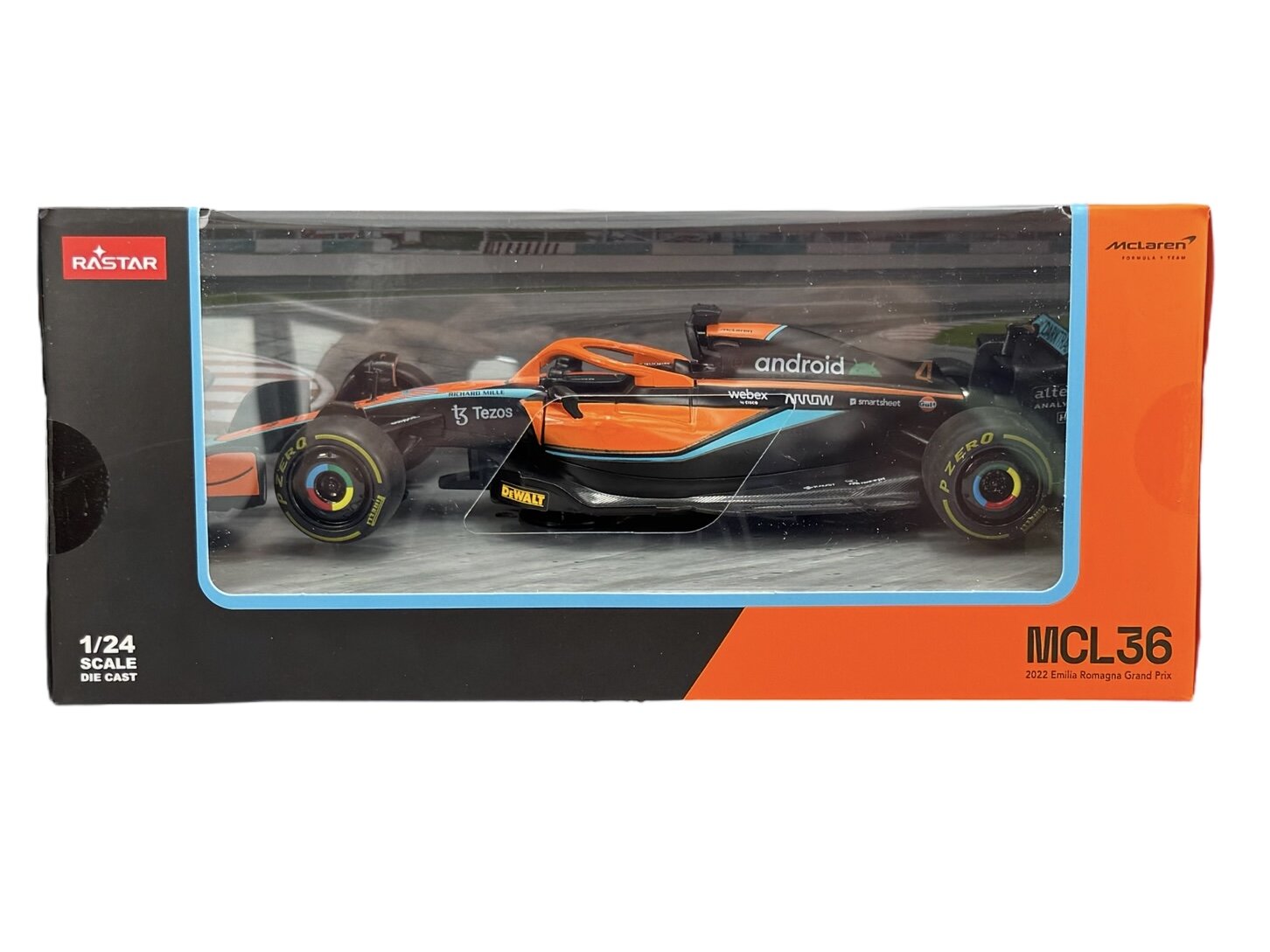 Model samochodu wyścigowego w skali 1/24 w opakowaniu z logo Rastar i napisami \'MCL36\' oraz \'2022 Emilia Romagna Grand Prix\'. Widoczne są detale samochodu, takie jak pomarańczowo-czarne malowanie i logotypy sponsorów.