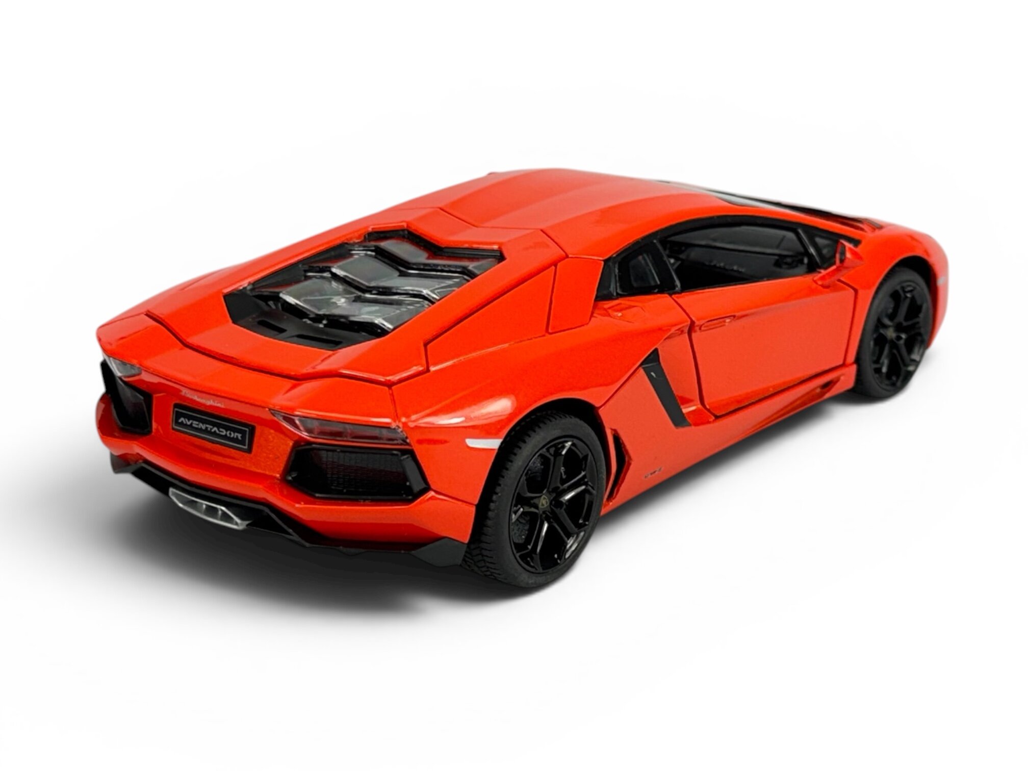 Model samochodu w kolorze pomarańczowym, przedstawiający sportowy pojazd z czarnymi felgami i widocznym napisem \'Aventador\' z tyłu. Samochód ma szczegółowo odwzorowane elementy, takie jak tylne światła i wydech.