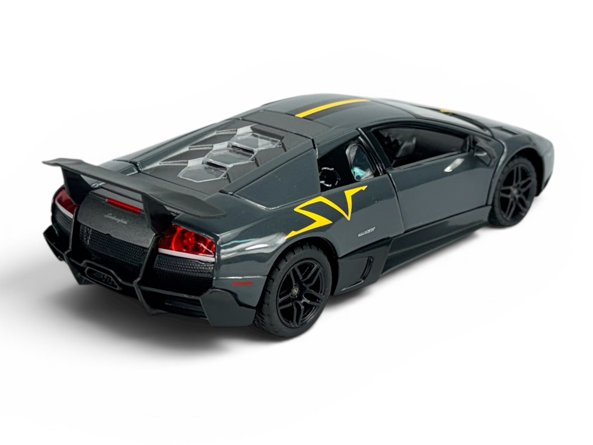 Model samochodu w skali 1:24 przedstawiający szary pojazd sportowy z żółtymi detalami i dużym tylnym spojlerem. Na tylnej części widoczny jest napis \'Lamborghini\'.