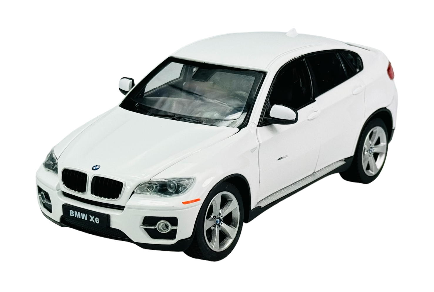 Model samochodu w kolorze białym z widocznym logo BMW na masce. Na tablicy rejestracyjnej widnieje napis \'BMW X6\'.
