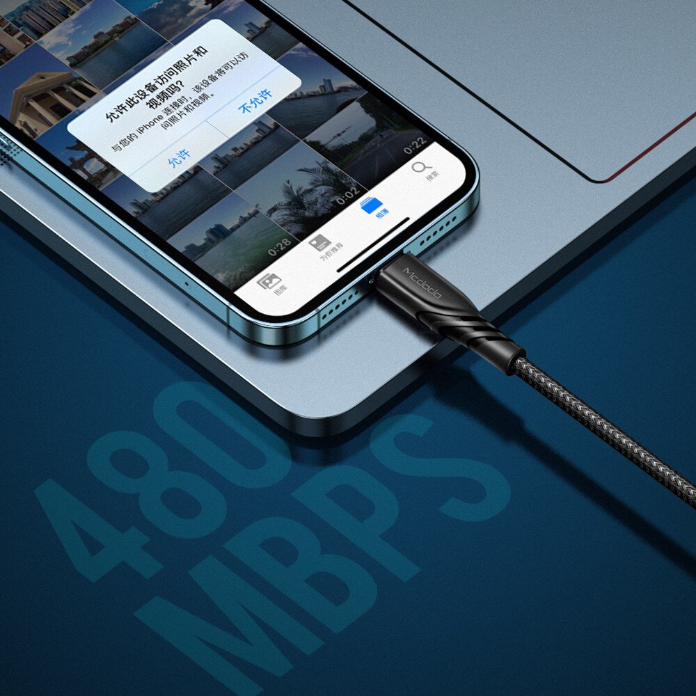 Telefon podłączony do kabla USB-C Lightning, na ekranie widoczne są zdjęcia i komunikat w języku chińskim. Na kablu widoczne jest logo \'Mcdodo\', a na tle napis \'480 MBPS\'.