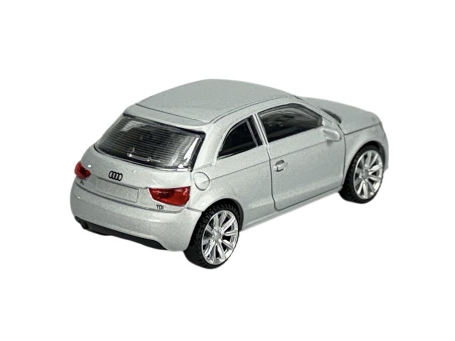 Model samochodu w skali 1:43 przedstawiający srebrny pojazd z logo Audi na tylnej klapie. Samochód ma szczegółowe elementy, takie jak reflektory i felgi.
