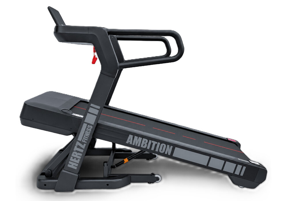 Na obrazie widoczna jest bieżnia elektryczna z napisem \'HERTZ FITNESS\' i \'AMBITION\' na bocznej części. Bieżnia ma czarną konstrukcję z czerwonymi akcentami na pasie biegowym.