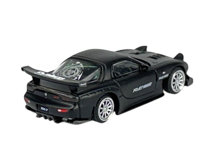 Czarny model samochodu sportowego z widocznym napisem \'RE Amemiya\' na boku i \'RX-7\' na tablicy rejestracyjnej. Samochód ma duży tylny spojler i srebrne felgi.