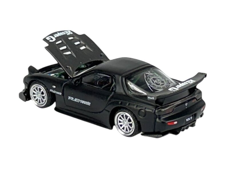 Czarny model samochodu w skali 1:64 z otwartą maską i widocznymi detalami na karoserii, takimi jak napisy \'R.E-Amemiya\' i \'RX-7\'. Na tylnej szybie i spoilerze znajdują się białe napisy oraz wzory.