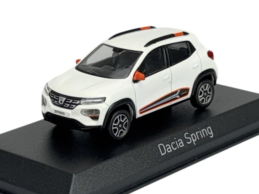 Model samochodu w kolorze białym z pomarańczowymi akcentami, umieszczony na czarnej podstawce z napisem \'Dacia Spring\'.