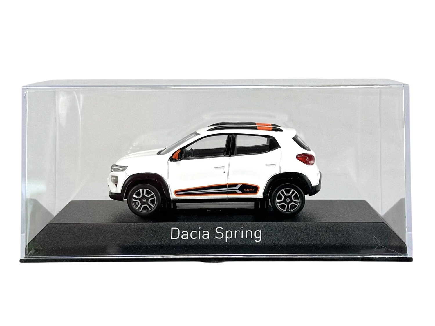 Model samochodu Dacia Spring w kolorze białym, umieszczony w przezroczystej gablocie. Na podstawce widoczny jest napis \'Dacia Spring\'.