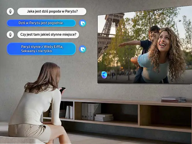 Kobieta siedzi na kanapie i patrzy na telewizor, na którym wyświetlany jest obraz kobiety z dzieckiem na tle Wieży Eiffla. Obok telewizora widoczne są dymki z tekstem: \'Jaka jest dziś pogoda w Paryżu?\', \'Dziś w Paryżu jest pogodnie.\', \'Czy jest tam jakieś słynne miejsce?\', \'Paryż słynie z Wieży Eiffla, Sekwany i nie tylko.\'.