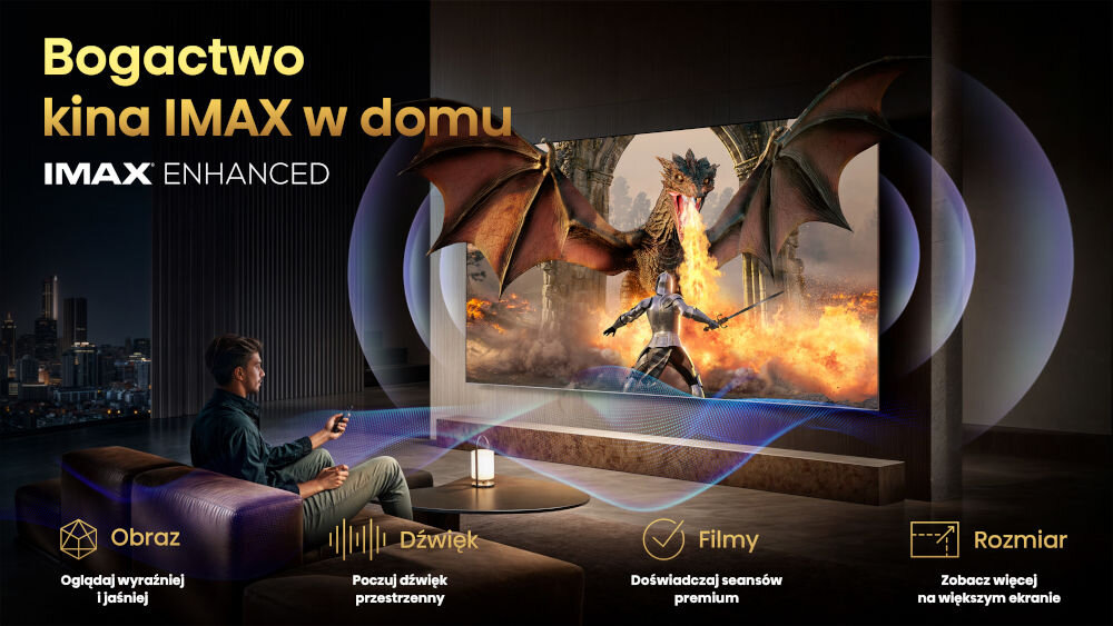 Obraz przedstawia osobę siedzącą na kanapie przed dużym telewizorem, na którym wyświetlana jest scena z gry lub filmu z smokiem. Na obrazie widnieje tekst: \'Bogactwo kina IMAX w domu\', \'IMAX ENHANCED\', oraz opisy funkcji: \'Obraz - Oglądaj wyraźniej i jaśniej\', \'Dźwięk - Poczuj dźwięk przestrzenny\', \'Filmy - Doświadczaj seansów premium\', \'Rozmiar - Zobacz więcej na większym ekranie\'.