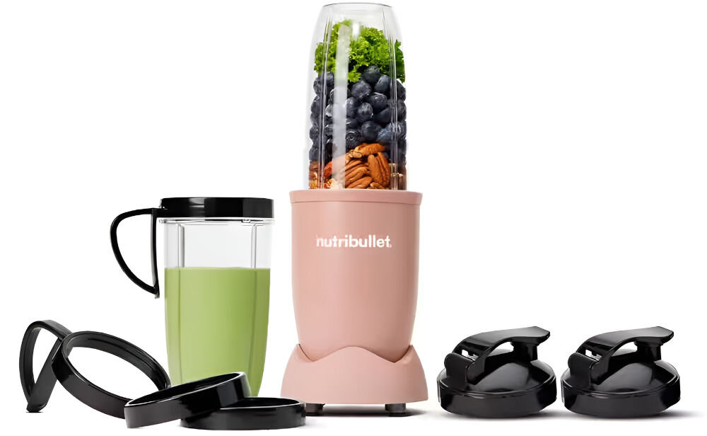 Na obrazie znajduje się różowy blender z logo \'nutribullet\', wypełniony owocami i warzywami. Obok znajdują się dodatkowe akcesoria, w tym kubek z zielonym napojem i czarne pokrywki.