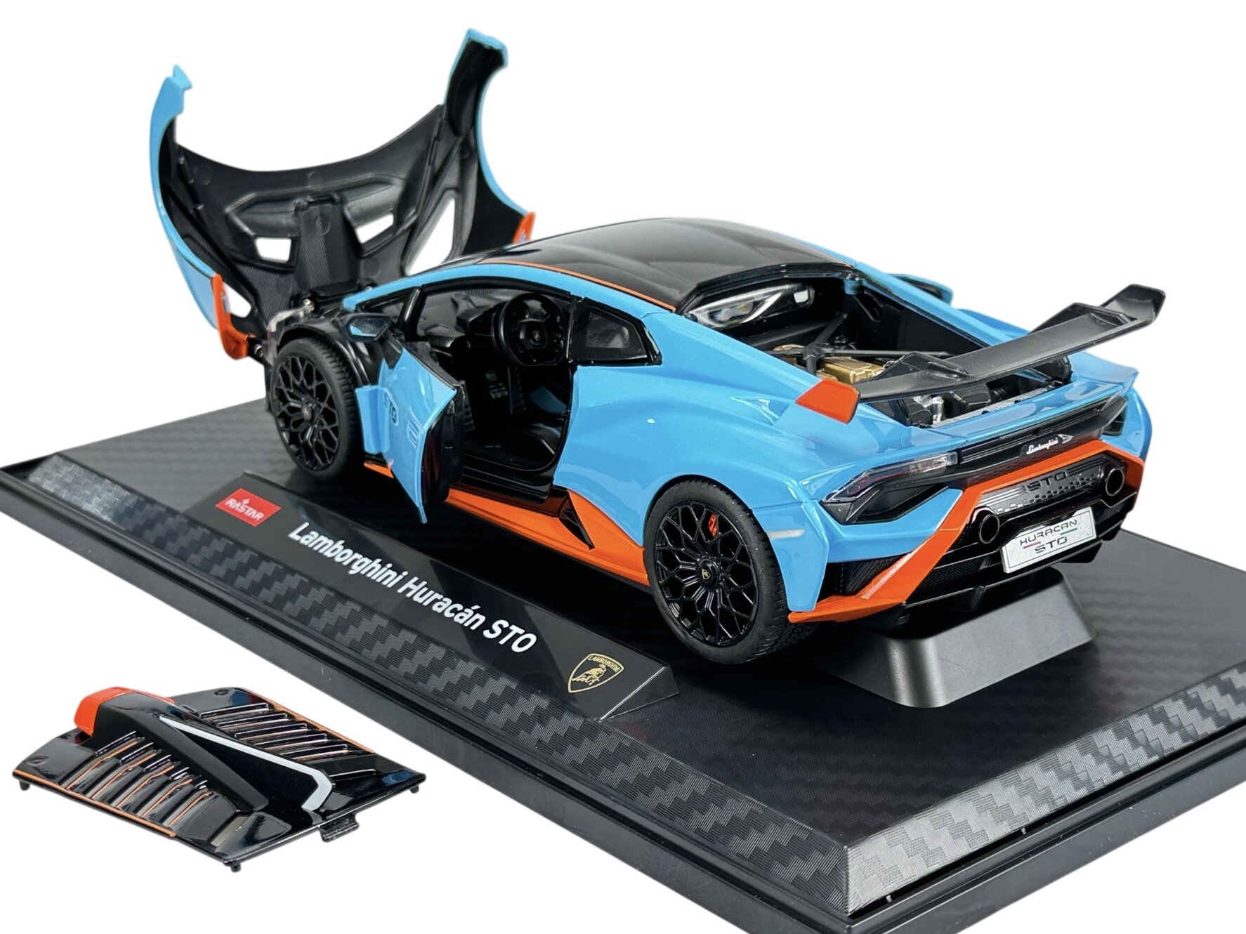 Model samochodu Lamborghini Huracan STO w kolorze niebieskim z pomarańczowymi akcentami, umieszczony na podstawce z napisem \'Lamborghini Huracán STO\'. Drzwi i maska są otwarte, a obok znajduje się dodatkowy element karoserii.