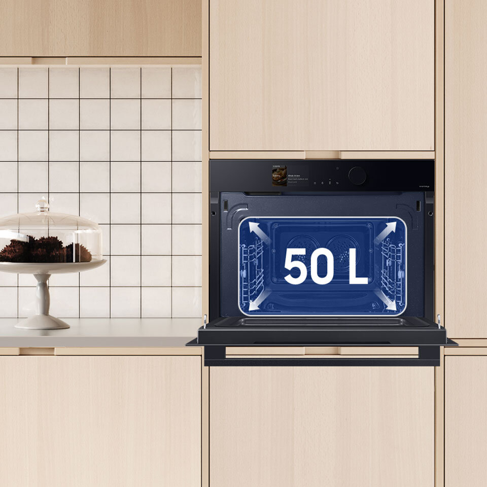 Zdjęcie w widoczny sposób prezentuje 50 l pojemności piekarnika kompaktowego Czarny piekarnik elektryczny z mikrofalą w zabudowie kuchennej, z otwartymi drzwiczkami i napisem \'50 L\' wewnątrz. Obok znajduje się patera z ciastem na tle białych płytek.