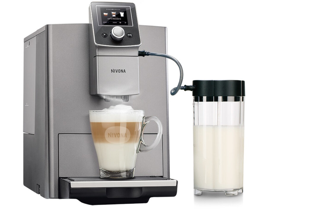 Ekspres do kawy w kolorze srebrnym z logo NIVONA, z filiżanką kawy z mleczną pianką oraz pojemnikiem na mleko. Na wyświetlaczu widoczny jest napis \'LATTE MACCHIATO\'.