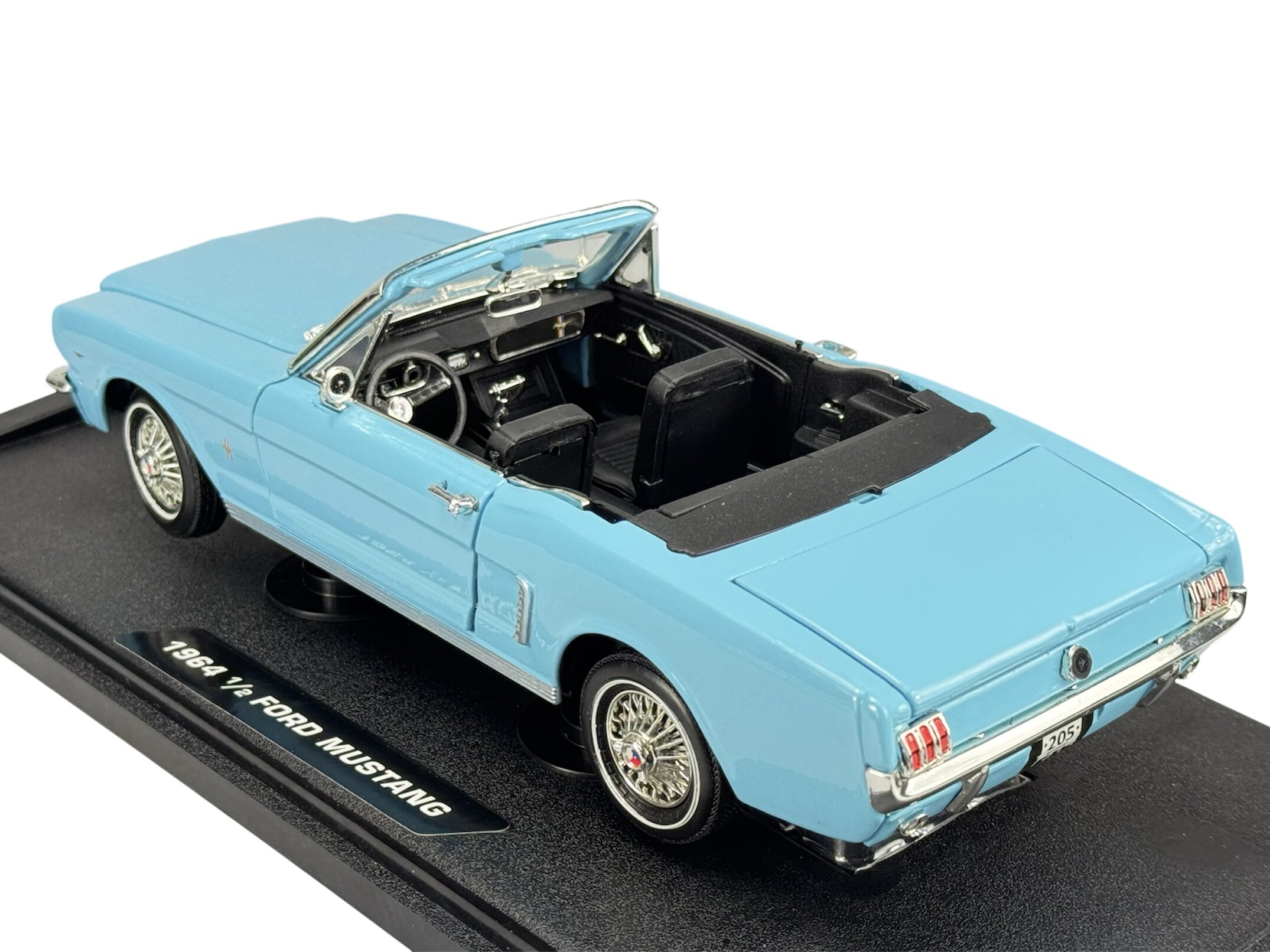 Model samochodu w kolorze niebieskim przedstawia kabriolet z otwartym dachem i szczegółowym wnętrzem. Na podstawce widnieje napis \'1964 1/2 Ford Mustang\'.