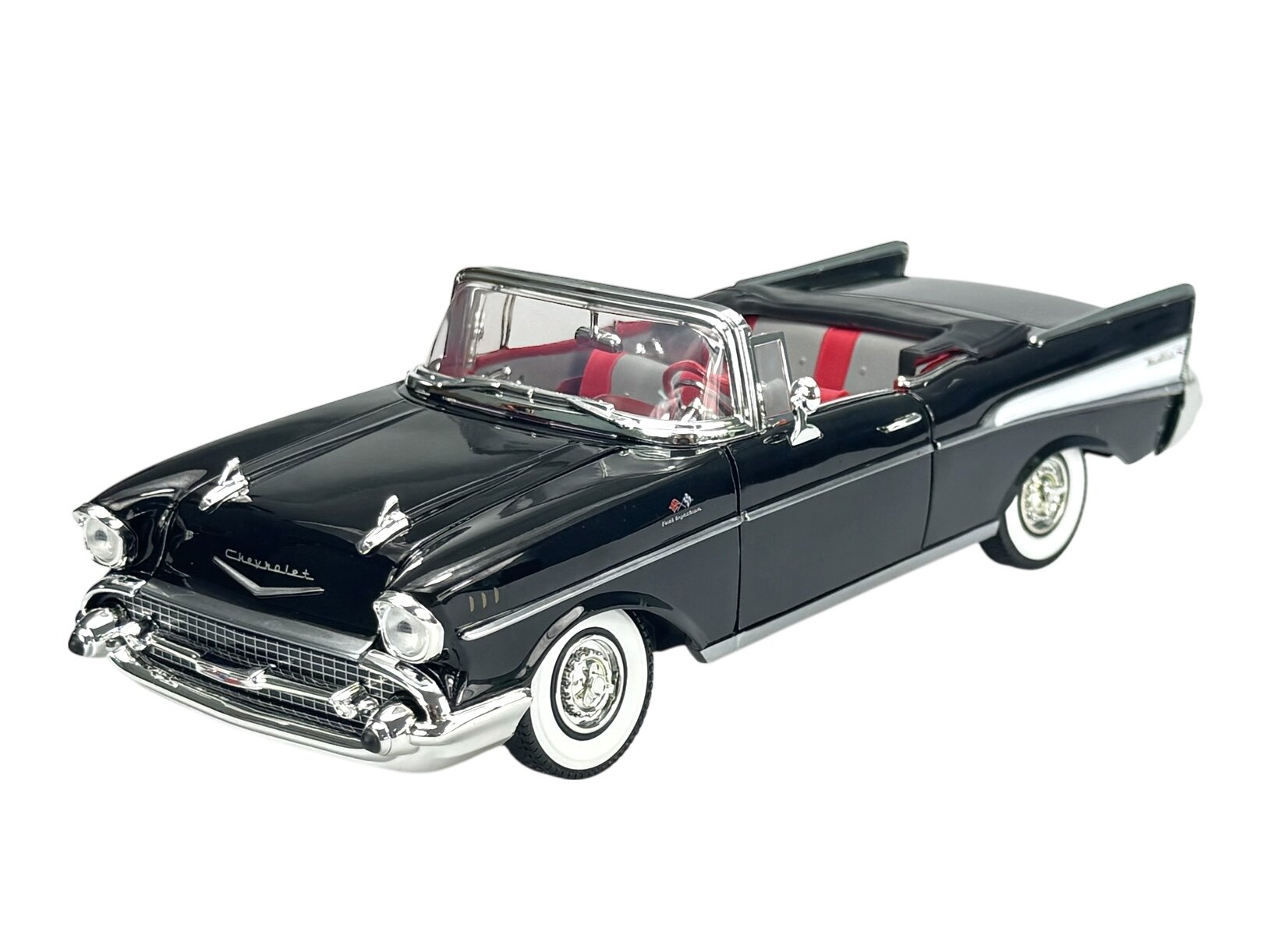 Model samochodu w skali 1:18 przedstawiający czarny kabriolet z 1957 roku z czerwonym wnętrzem. Na masce widoczne jest logo \'Chevrolet\'.