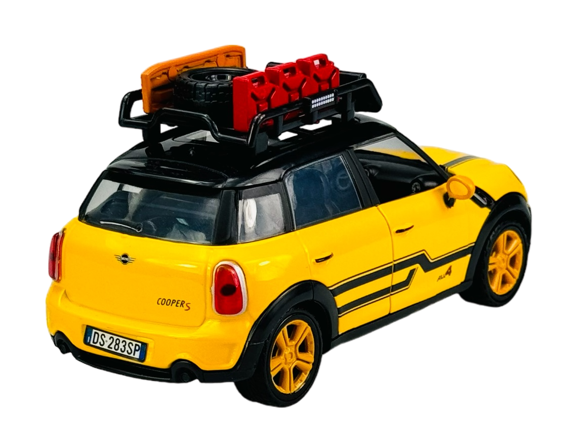 Żółty model samochodu z czarnymi i pomarańczowymi detalami, z bagażnikiem dachowym zawierającym koło zapasowe i czerwone kanistry. Na tylnej klapie widoczny napis \'COOPER S\' oraz tablica rejestracyjna \'DS-283SP\'.