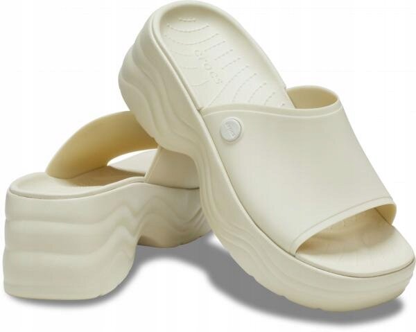 Para beżowych klapek na platformie z falistym wzorem na podeszwie. Na jednym z klapek widoczne jest logo \'crocs\'.