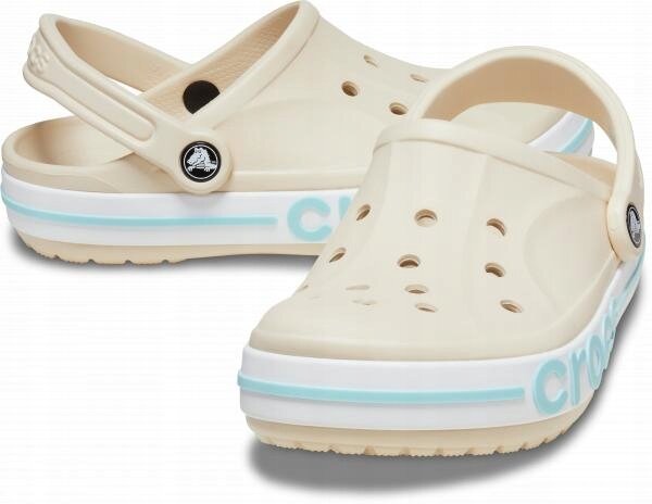 Beżowe chodaki z otworami wentylacyjnymi i paskiem na piętę. Na boku podeszwy widoczny jest napis \'crocs\'.