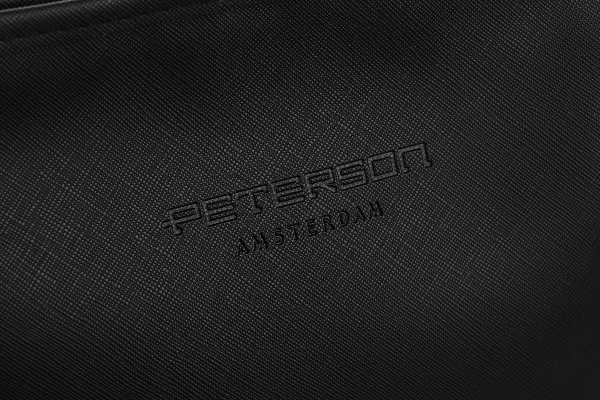 Czarna powierzchnia z wytłoczonym napisem \'PETERSON AMSTERDAM\'.