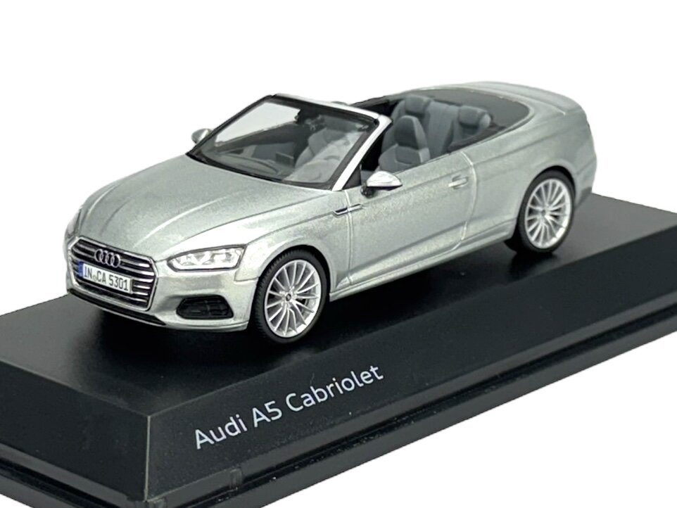 Model samochodu Audi A5 Cabriolet w kolorze srebrnym, umieszczony na czarnej podstawce z napisem \'Audi A5 Cabriolet\'.