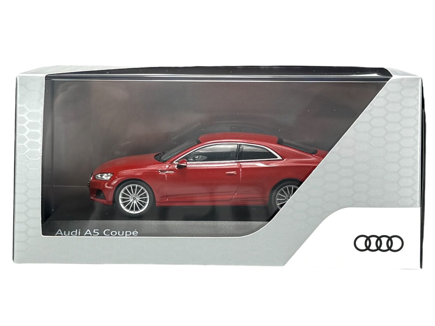 Model samochodu Audi A5 Coupé w kolorze czerwonym znajduje się w przezroczystym opakowaniu. Na opakowaniu widoczne jest logo Audi oraz napis \'Audi A5 Coupé\'.