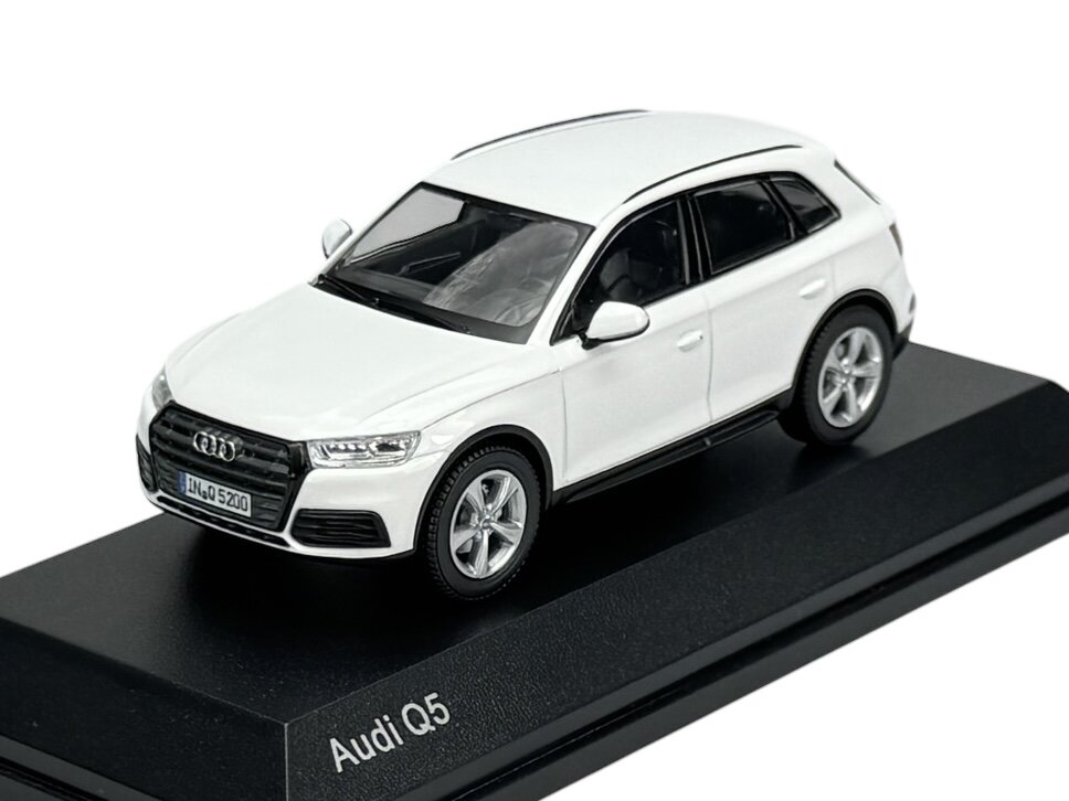 Model samochodu Audi Q5 w kolorze białym, umieszczony na czarnej podstawce z napisem \'Audi Q5\'.