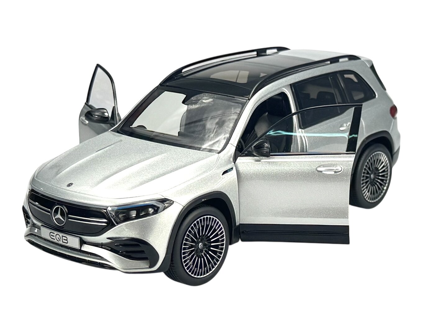 Model samochodu w kolorze srebrnym z otwartymi drzwiami, widoczne logo Mercedes-Benz na masce oraz napis EQB na tablicy rejestracyjnej.