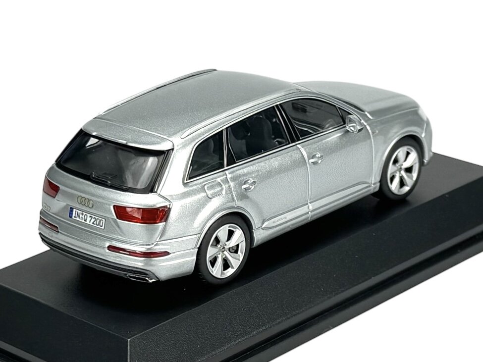 Model samochodu w kolorze srebrnym na czarnej podstawce, z widocznym logo Audi i tablicą rejestracyjną \'IN-Q 7200\'.