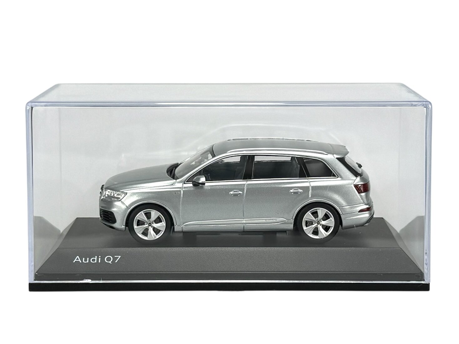 Model samochodu Audi Q7 w kolorze srebrnym, umieszczony w przezroczystej gablocie. Na podstawce widoczny jest napis \'Audi Q7\'.