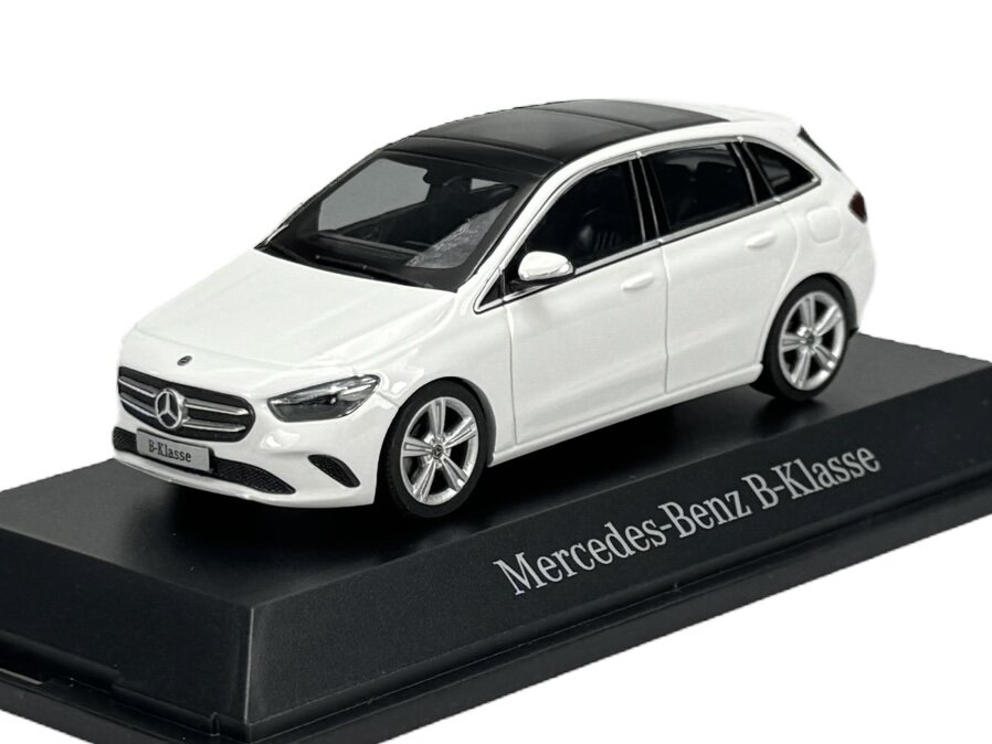 Model samochodu Mercedes-Benz B-Klasse w kolorze białym, umieszczony na czarnej podstawce z napisem \'Mercedes-Benz B-Klasse\'.