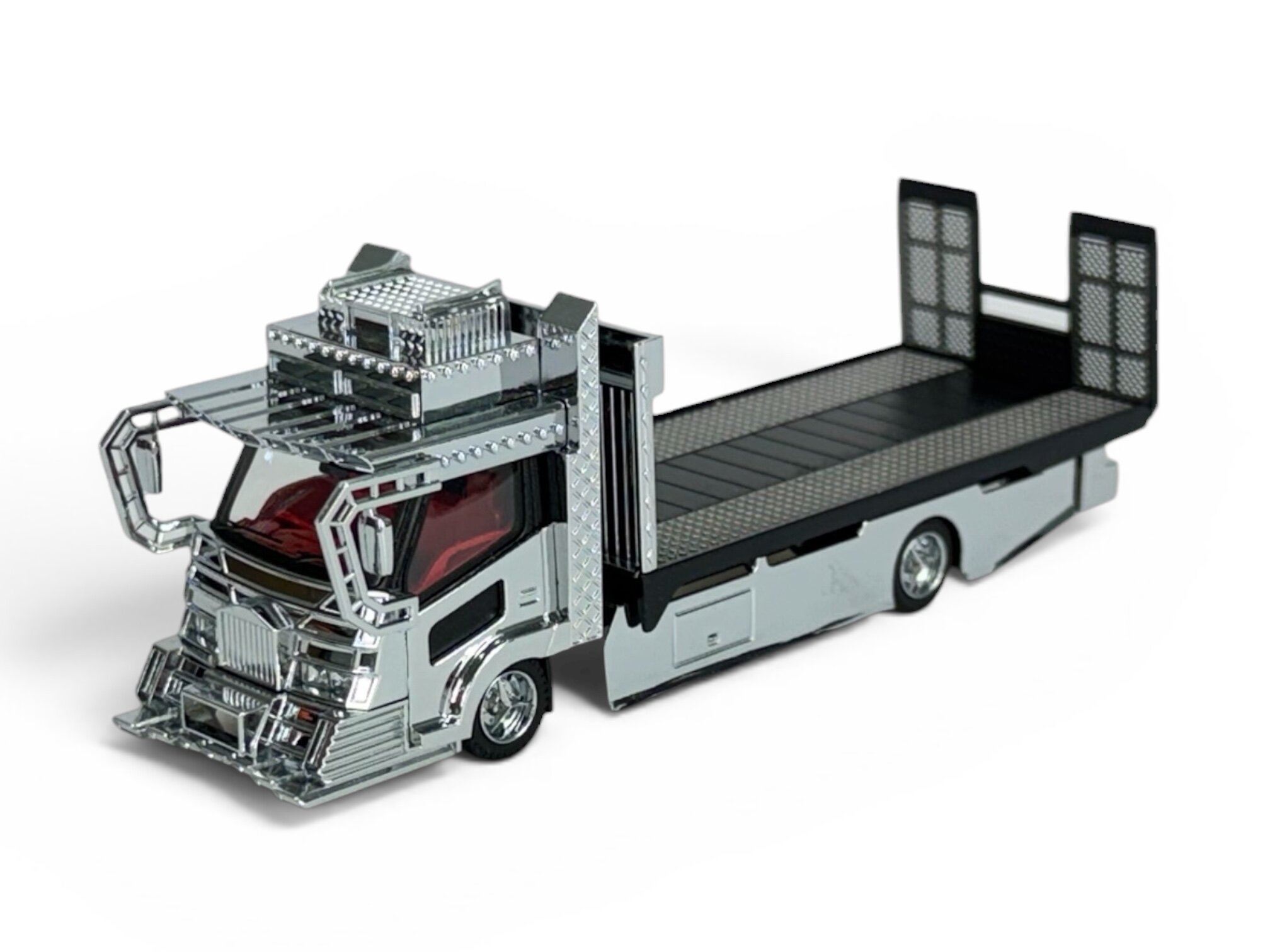 Model metalowej lawety w skali 1:64 z chromowanymi elementami i czerwonymi szybami. Pojazd ma szczegółowo wykonane detale i czarną platformę ładunkową.