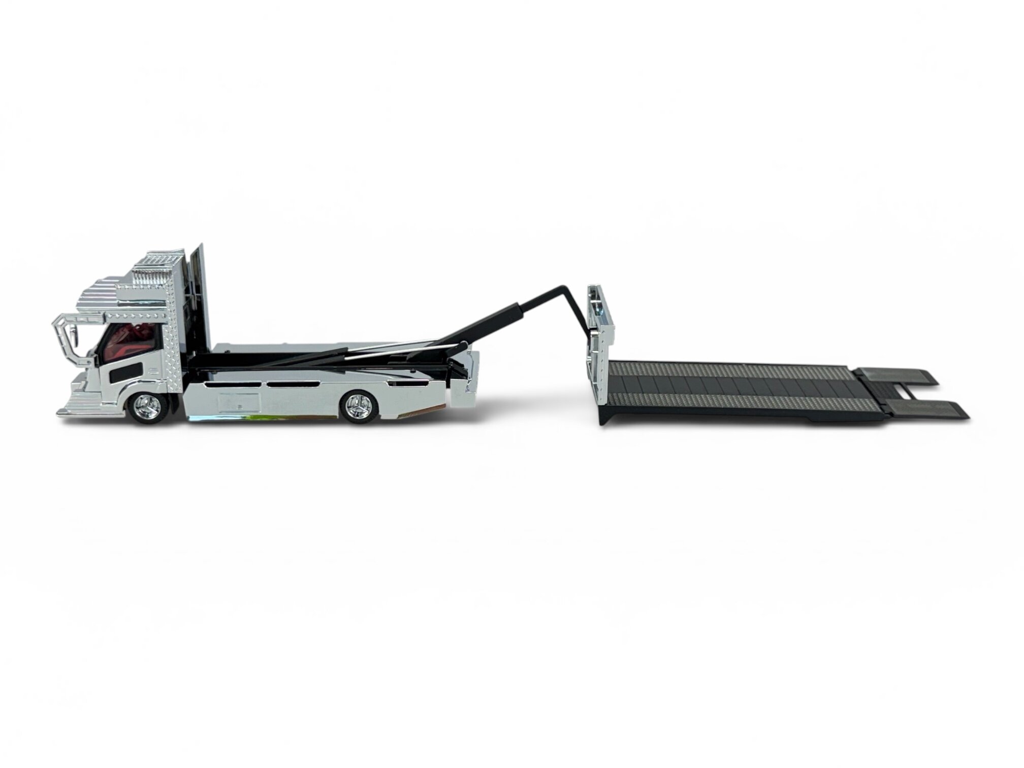 Model metalowej lawety w skali 1:64 z wysuniętą rampą, w kolorze srebrnym z czarnymi elementami. Pojazd ma szczegółowo odwzorowaną kabinę i koła.