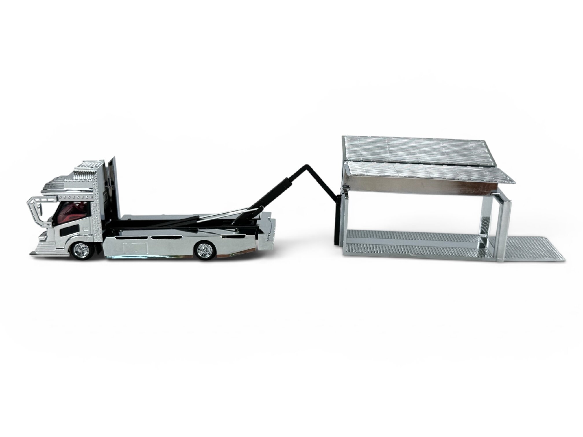 Model metalowego samochodu ciężarowego z kontenerem w skali 1:64, w kolorze srebrnym, z widocznym mechanizmem podnoszenia kontenera.
