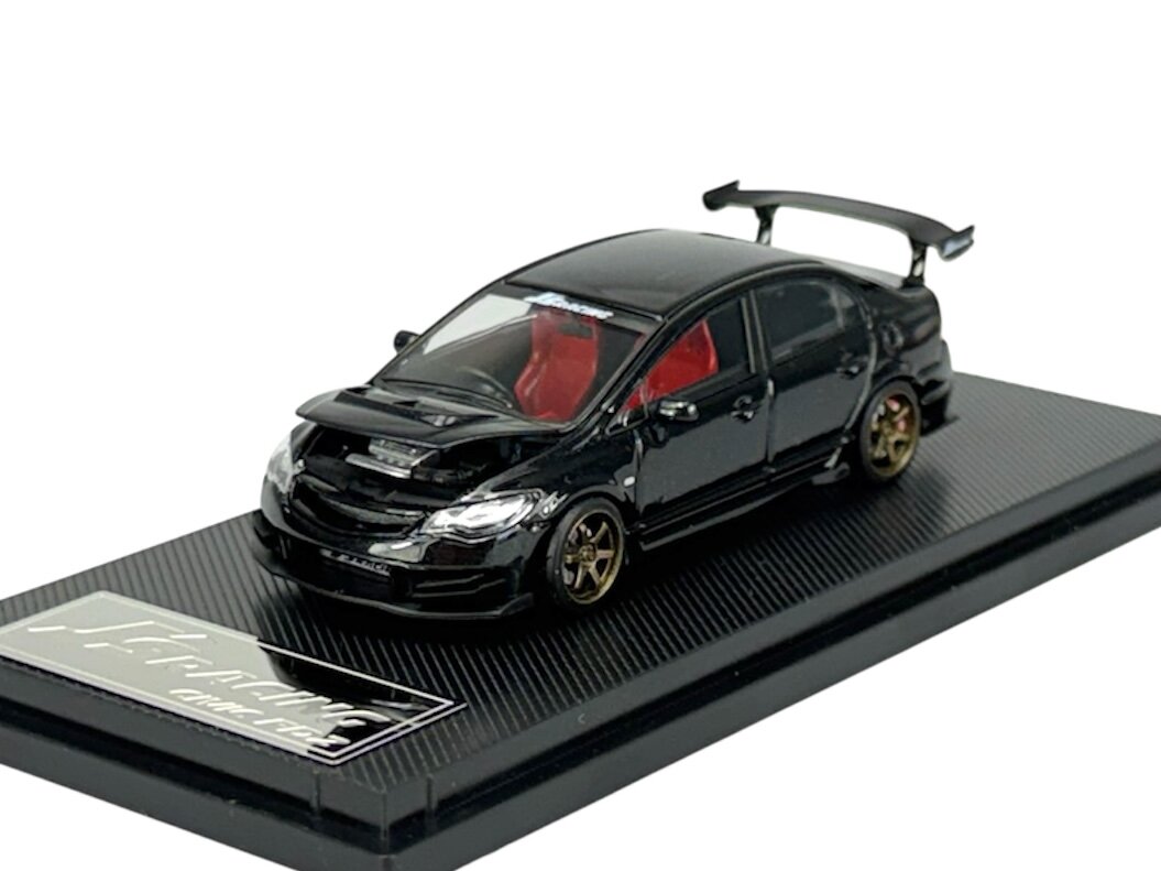 Model samochodu w skali 1:64 przedstawiający czarny pojazd z otwartą maską i czerwonym wnętrzem, umieszczony na podstawce z napisem \'J\'s Racing\'.