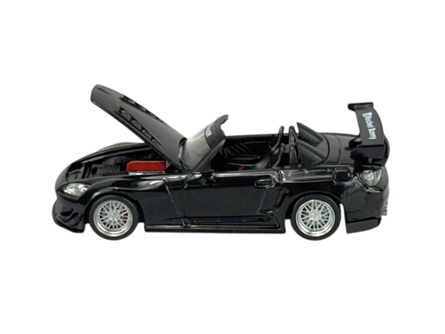Model samochodu w skali 1:64 przedstawiający czarny sportowy kabriolet z otwartą maską i widocznym wnętrzem. Na tylnym spojlerze widnieje napis \'Rocket Bunny\'.