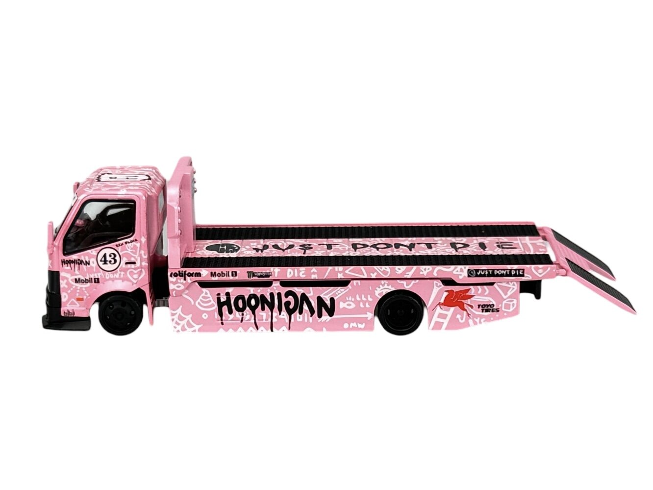 Różowa ciężarówka z grafiką i napisami, w tym \'HOONIGAN\' oraz \'JUST DON\'T DIE\'. Na pojeździe widoczne są także logotypy, takie jak Mobil 1 i Rotiform.
